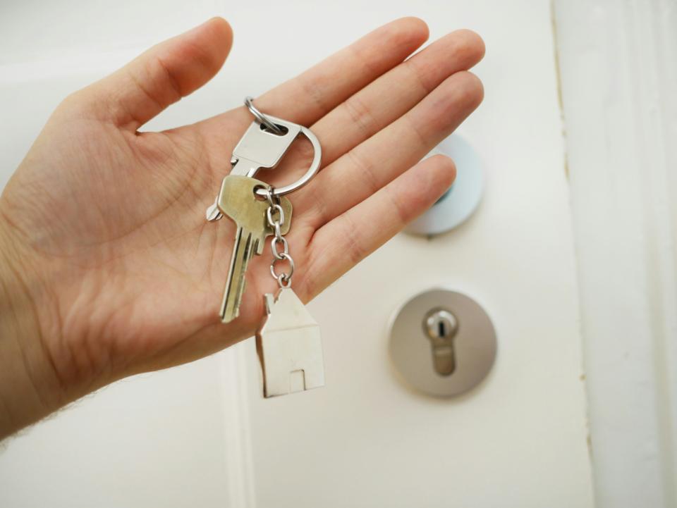 Hand holding keys with house keychain