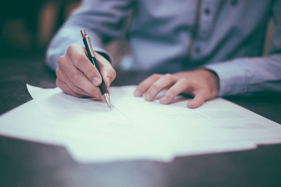 Person writing on papers with a pen